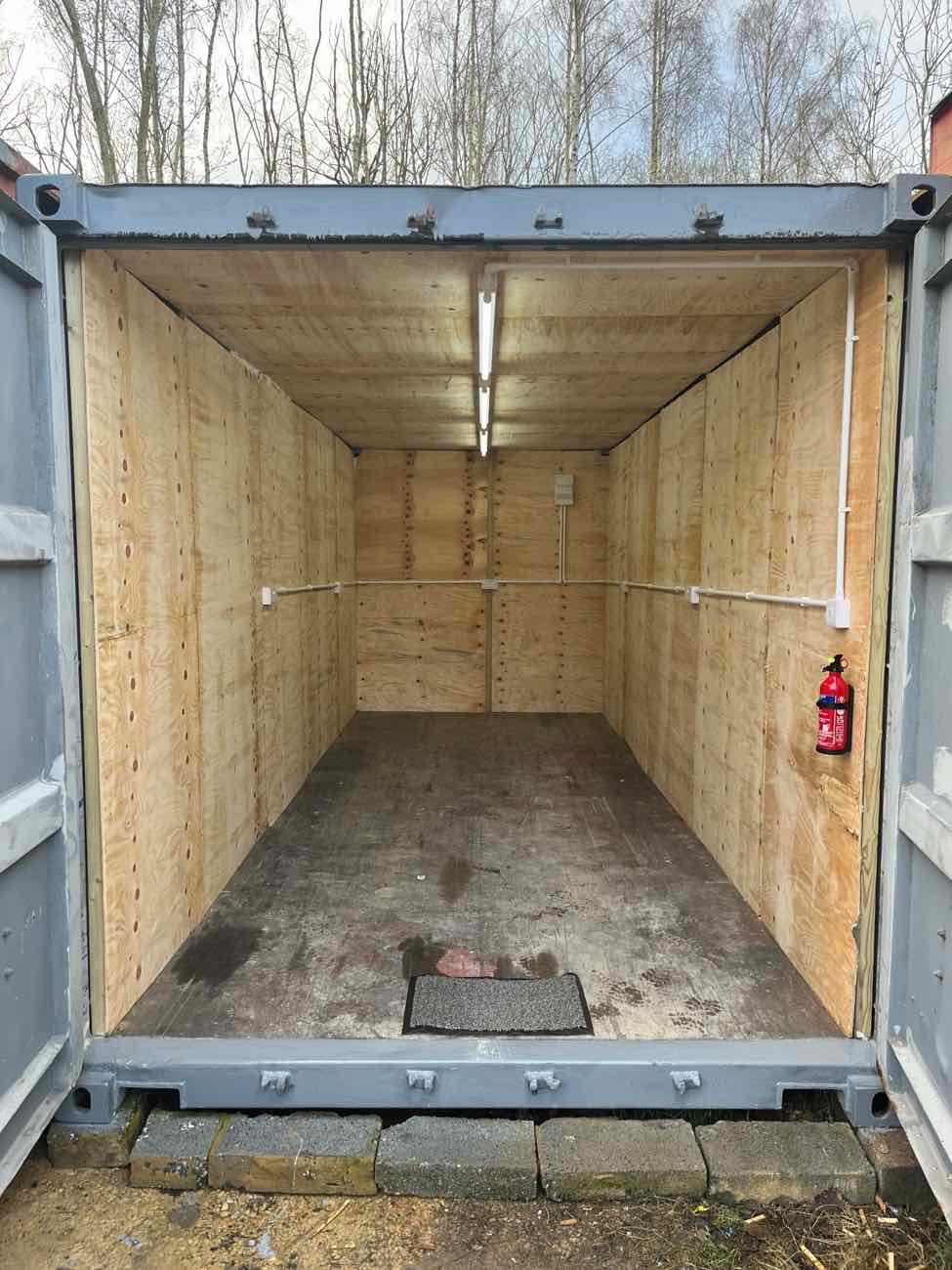 Inside a GABA unit: plywood-lined walls, strip light and power trunking